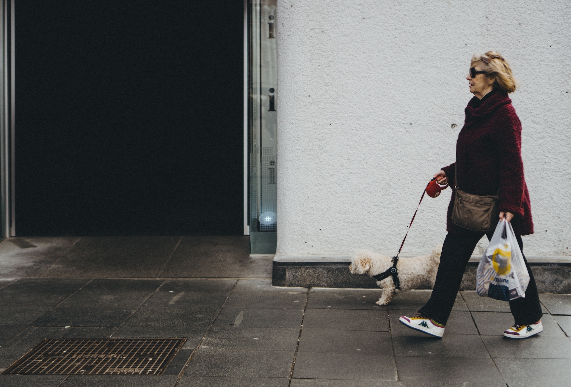 Elderly woman walking on sidewalk.
