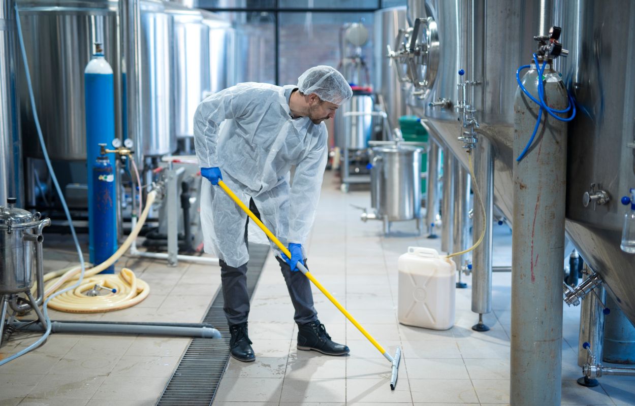 Worker cleaning floor of an industrial facility