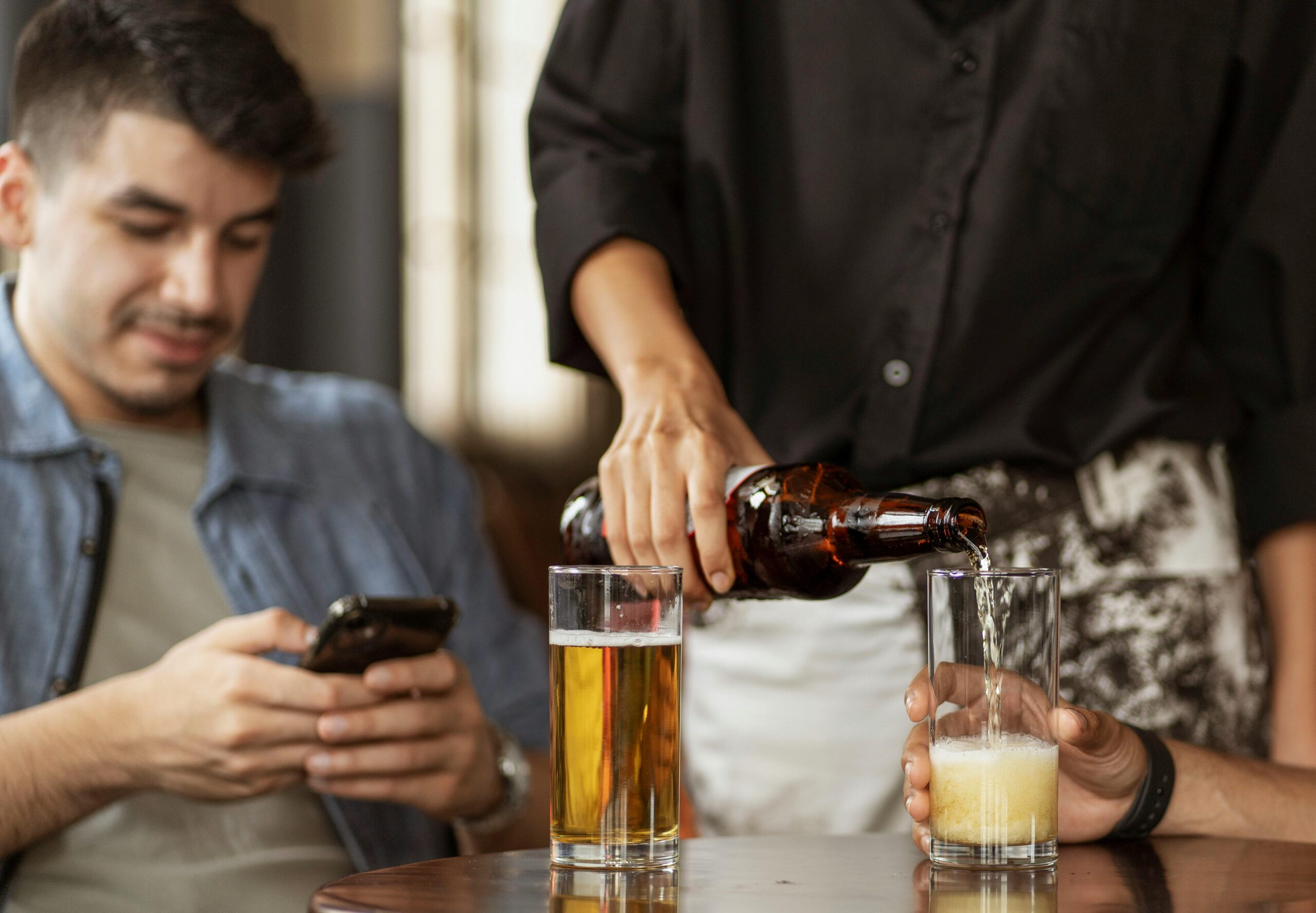 Young man using cell phone at a bar with friends.